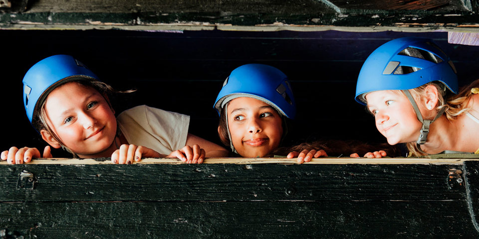 Tre barn som har hjälm på sig för att de ska på ett äventyr på kollo 